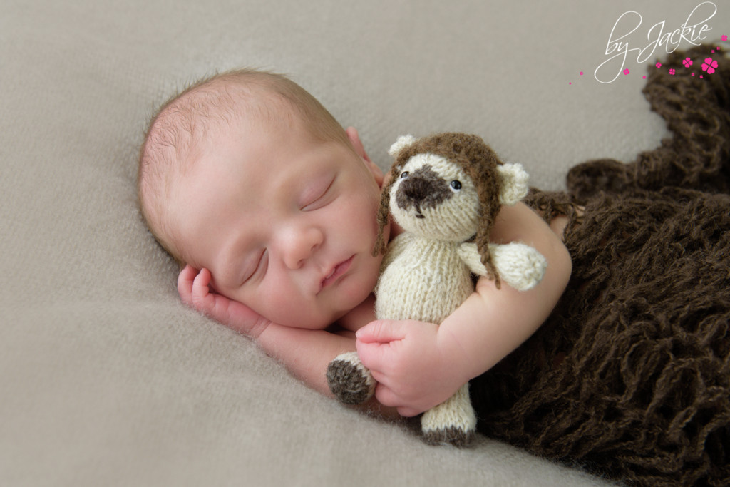 Photo of a newborn baby wrapped in chocolate brown mohair wrap cuddling his hand-knitted teddy bear. Image copyright By Jackie Photography in York, UK