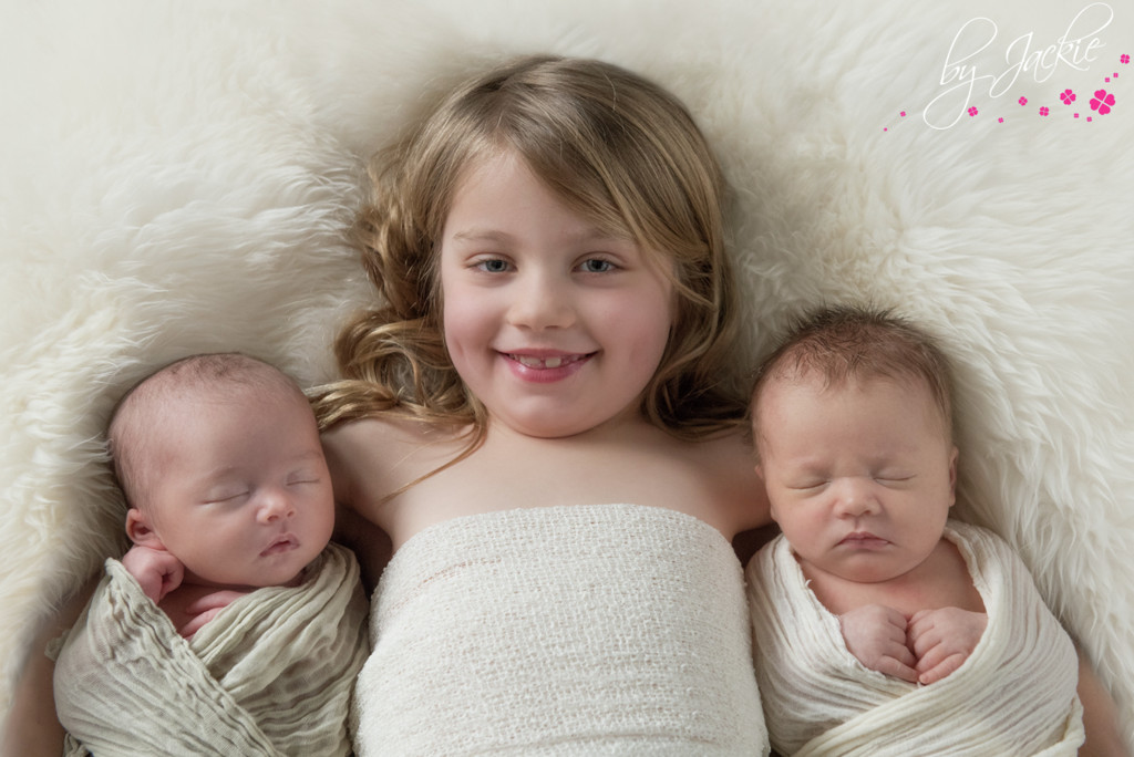 Photo of little girl cuddling her newborn baby twin sisters. Image copyright By Jackie Photography, Goole, UK